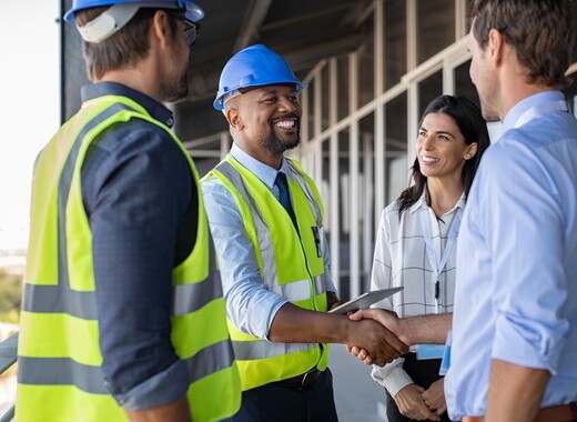 SageGlass team members shaking hands with client and smart glass windows in the back.